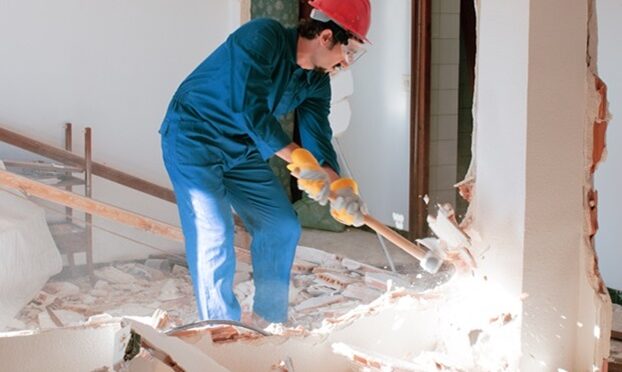 young worker with a red protection helmet and wearing a blue boiler suit. demolition concept