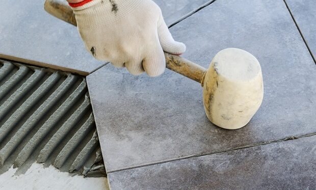 Laying Ceramic Tiles. Worker putting tiles on the balcony.